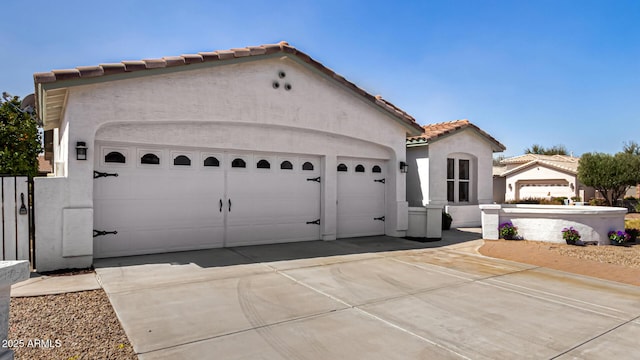 view of front of property with a garage, driveway, a tile roof, and stucco siding