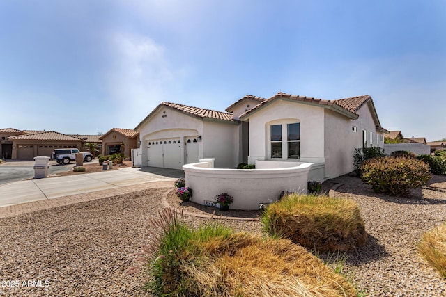 mediterranean / spanish-style home featuring driveway, an attached garage, a tiled roof, and stucco siding