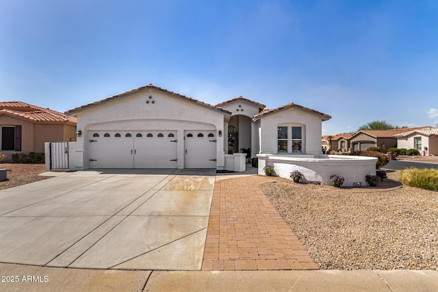 mediterranean / spanish-style house with a garage, concrete driveway, a tile roof, and stucco siding