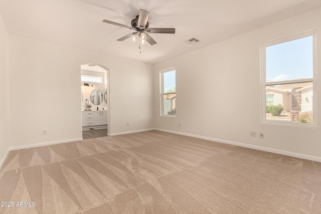 carpeted empty room with baseboards, visible vents, and a ceiling fan