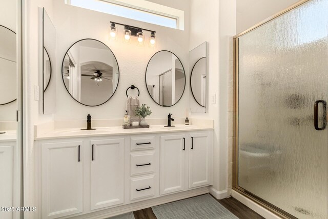 full bath with double vanity, a stall shower, and a sink