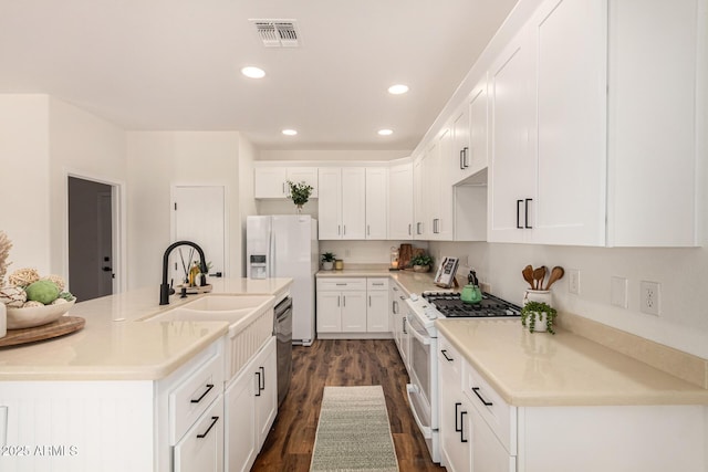 kitchen featuring white appliances, visible vents, white cabinetry, light countertops, and dark wood finished floors