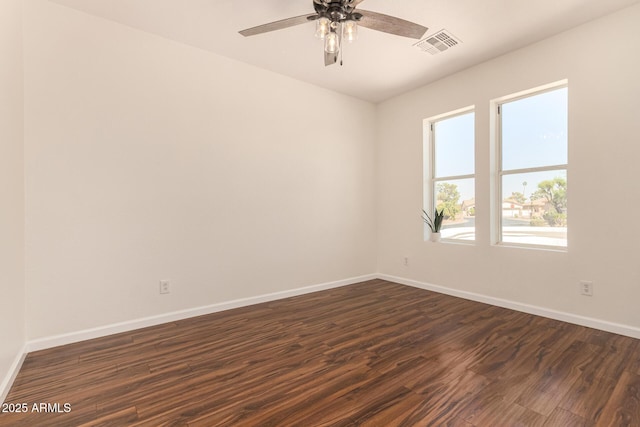 empty room featuring dark wood-style flooring, visible vents, ceiling fan, and baseboards