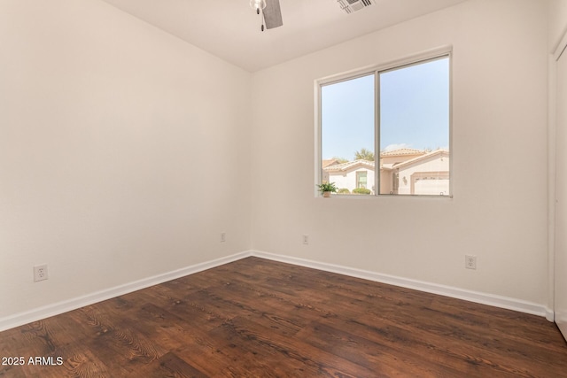 empty room with a ceiling fan, visible vents, dark wood finished floors, and baseboards