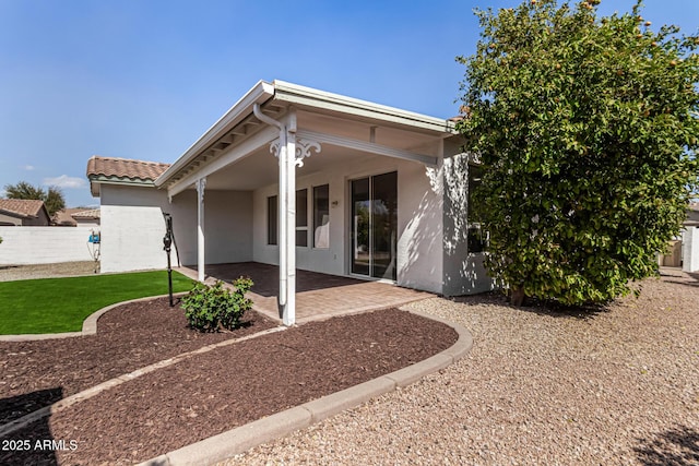 exterior space with stucco siding, fence, and a patio