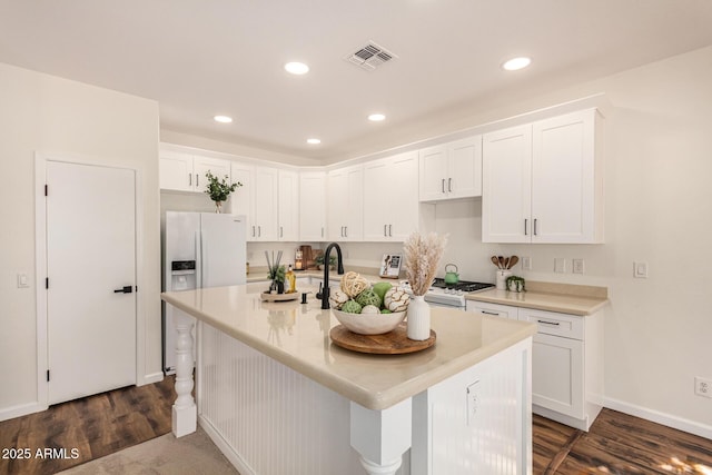 kitchen with visible vents, stove, dark wood-type flooring, white cabinetry, and white fridge with ice dispenser