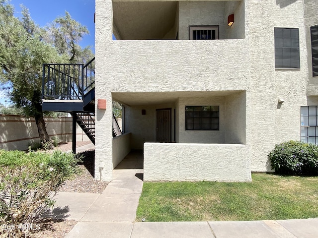 doorway to property featuring fence and stucco siding
