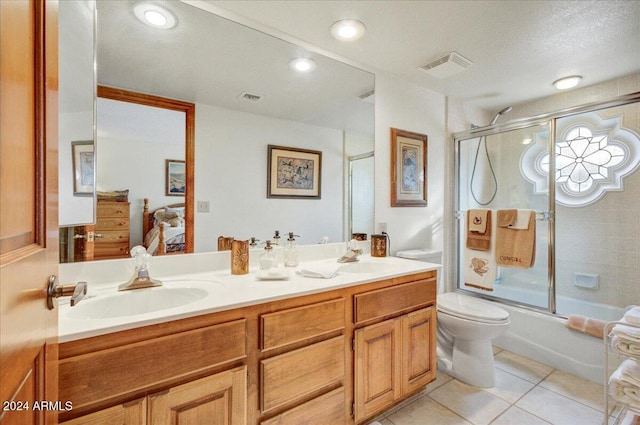 full bathroom with tile patterned floors, a textured ceiling, vanity, shower / bath combination with glass door, and toilet