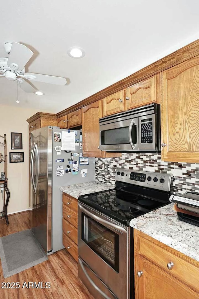 kitchen with a ceiling fan, tasteful backsplash, appliances with stainless steel finishes, and light wood-type flooring