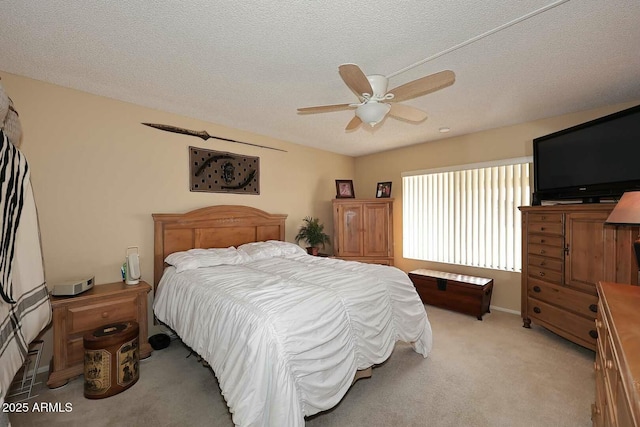 bedroom featuring light colored carpet, a textured ceiling, and ceiling fan