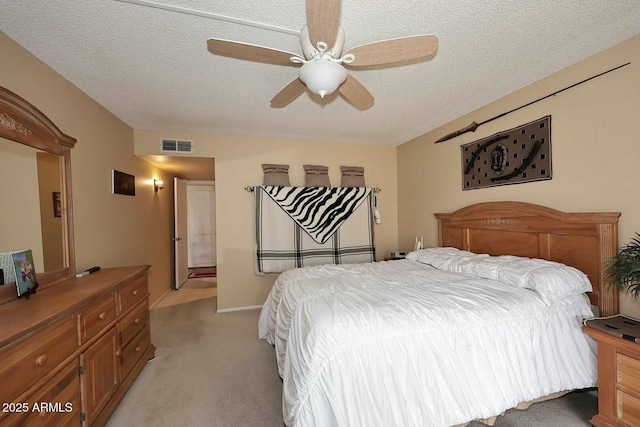 bedroom featuring a textured ceiling, a ceiling fan, visible vents, and light carpet