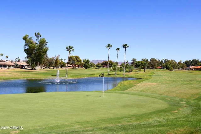 view of community with view of golf course, a yard, and a water view