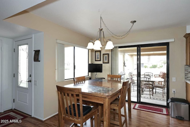 dining space featuring baseboards, a notable chandelier, and wood finished floors