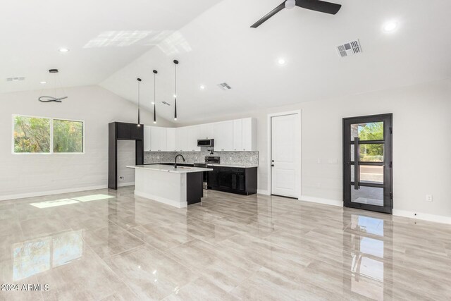 unfurnished living room with vaulted ceiling, a healthy amount of sunlight, sink, and ceiling fan