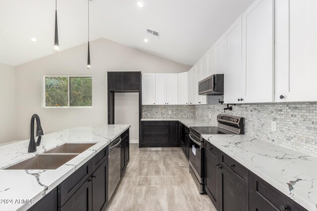 kitchen featuring light stone countertops, backsplash, appliances with stainless steel finishes, sink, and lofted ceiling