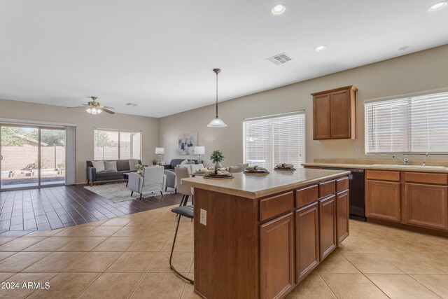 kitchen with ceiling fan, sink, hanging light fixtures, light hardwood / wood-style flooring, and a kitchen island