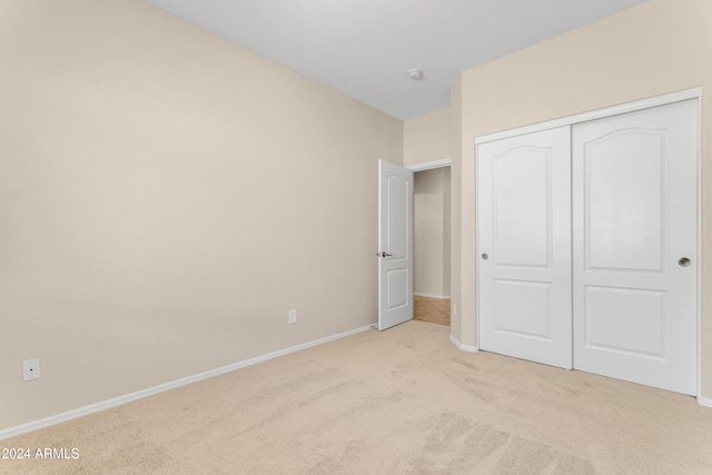 unfurnished bedroom featuring light colored carpet and a closet