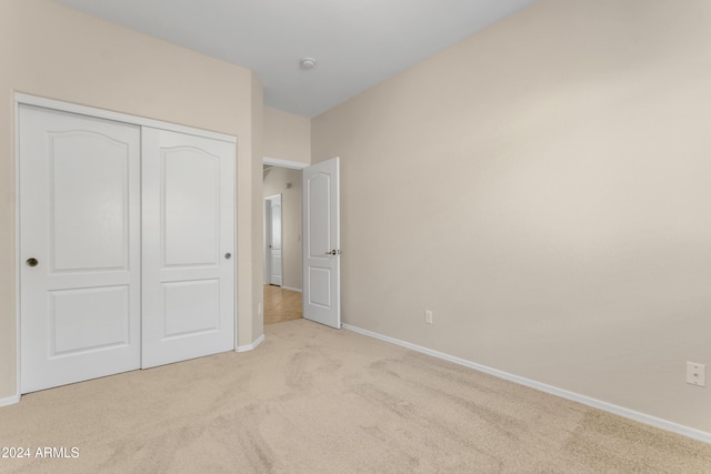 unfurnished bedroom with light carpet and a closet