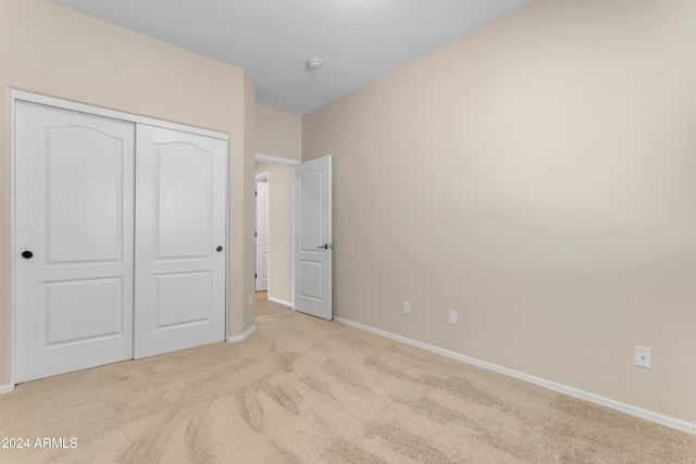 unfurnished bedroom featuring a closet and light colored carpet