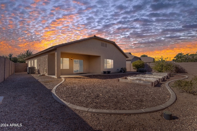 back house at dusk featuring cooling unit