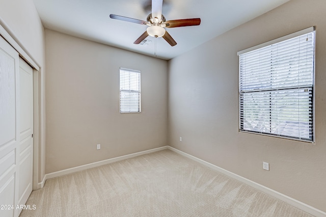 unfurnished bedroom with ceiling fan, light carpet, and a closet