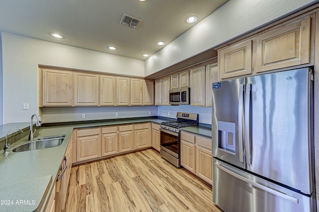 kitchen with appliances with stainless steel finishes, light brown cabinets, light hardwood / wood-style flooring, and sink