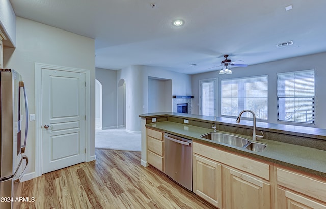 kitchen featuring appliances with stainless steel finishes, ceiling fan, sink, light brown cabinets, and light hardwood / wood-style flooring