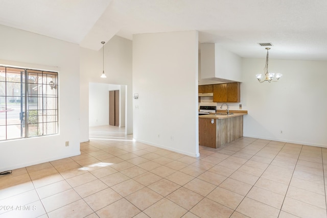 kitchen with an inviting chandelier, hanging light fixtures, light tile patterned floors, white range oven, and kitchen peninsula