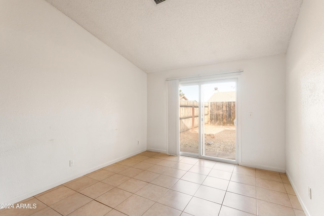 tiled spare room with a textured ceiling and vaulted ceiling