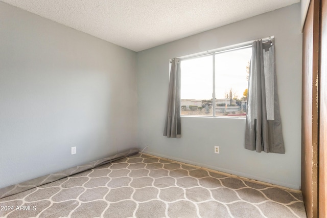 carpeted empty room featuring a textured ceiling