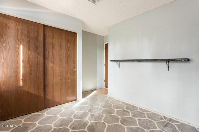 unfurnished bedroom featuring a textured ceiling and a closet