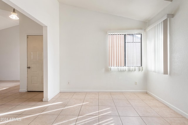 empty room featuring light tile patterned floors and lofted ceiling