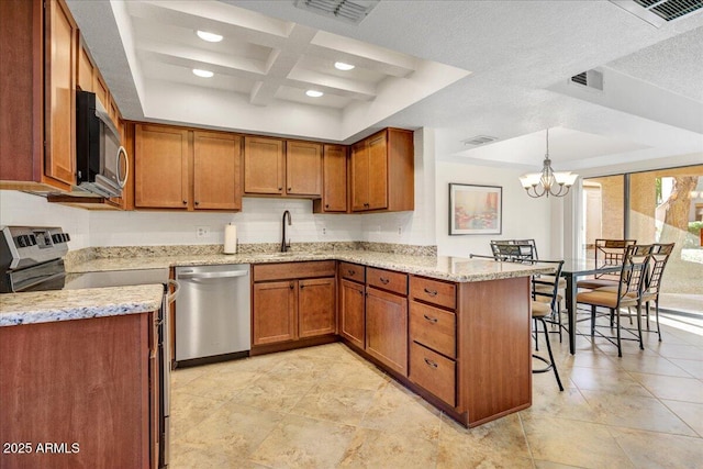 9450 N 94th Pl Unit 106, Scottsdale, AZ 85258 - kitchen featuring appliances with stainless steel finishes, a sink, brown cabinetry, coffered ceiling, and light stone counters