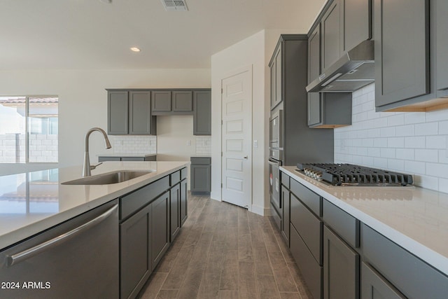 kitchen with dark wood-type flooring, sink, decorative backsplash, gray cabinets, and stainless steel appliances