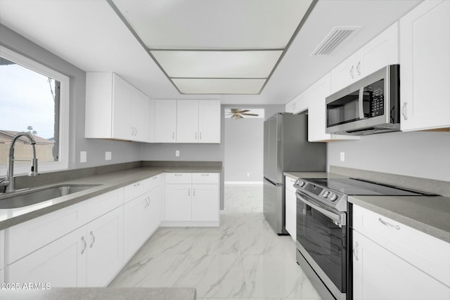 kitchen featuring a sink, visible vents, white cabinetry, marble finish floor, and appliances with stainless steel finishes