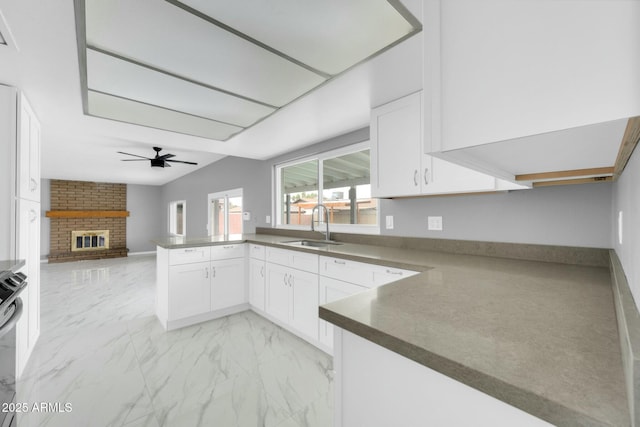 kitchen featuring open floor plan, a peninsula, marble finish floor, white cabinetry, and a sink