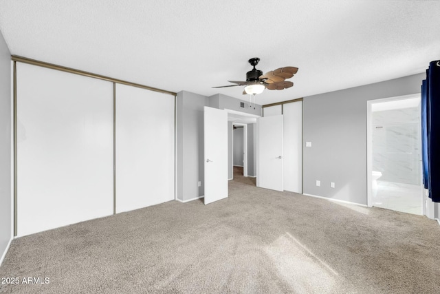 unfurnished bedroom featuring visible vents, ensuite bathroom, a textured ceiling, carpet floors, and multiple closets