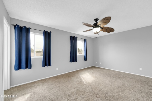 carpeted spare room with ceiling fan, baseboards, and a textured ceiling