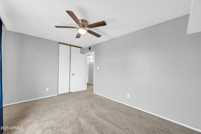 empty room with a textured ceiling, carpet floors, visible vents, a ceiling fan, and baseboards