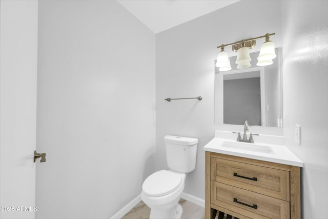 half bathroom featuring baseboards, vanity, and toilet