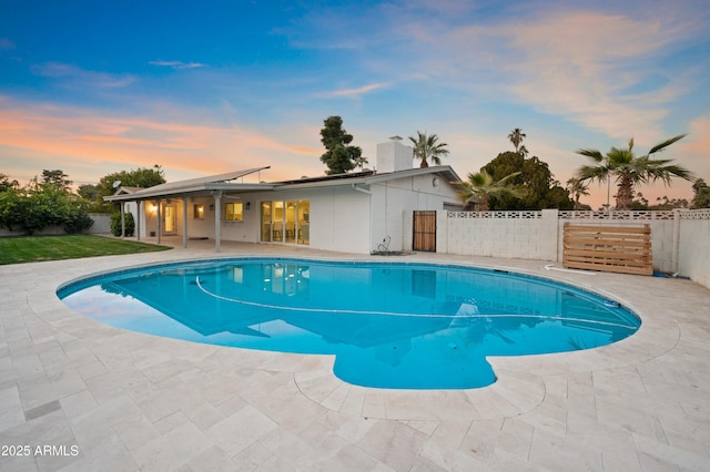 pool at dusk featuring a patio area