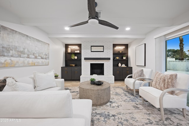 living room featuring hardwood / wood-style flooring, ceiling fan, a brick fireplace, and beam ceiling