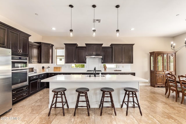 2457 E Melrose St, Mesa, AZ 85213 - kitchen featuring stainless steel appliances, a sink, a kitchen breakfast bar, light countertops, and an island with sink