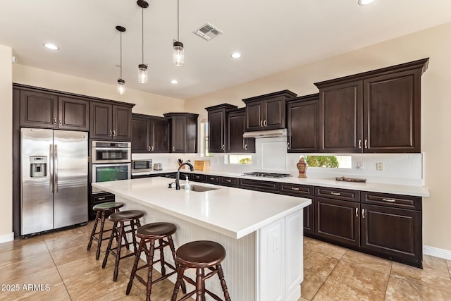 2457 E Melrose St, Mesa, AZ 85213 - kitchen with stainless steel appliances, a sink, a breakfast bar area, decorative light fixtures, and light countertops