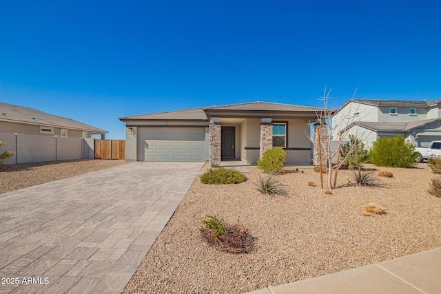 view of front of house featuring decorative driveway, an attached garage, fence, and stucco siding