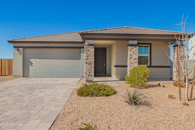 prairie-style house featuring decorative driveway, a tile roof, stucco siding, an attached garage, and stone siding