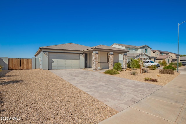 view of front of property featuring fence, a garage, a residential view, stone siding, and driveway