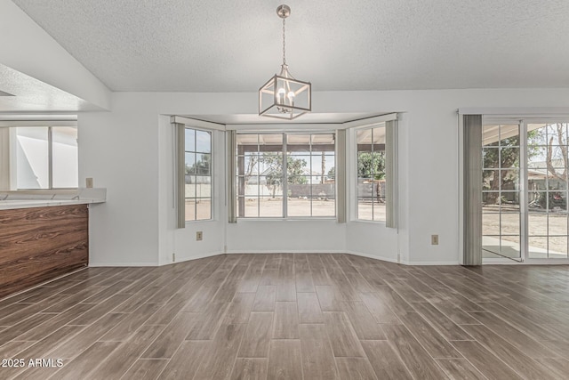 6701 W Monterey Way, Phoenix, AZ 85033 - unfurnished dining area featuring a textured ceiling, wood finished floors, a chandelier, and baseboards
