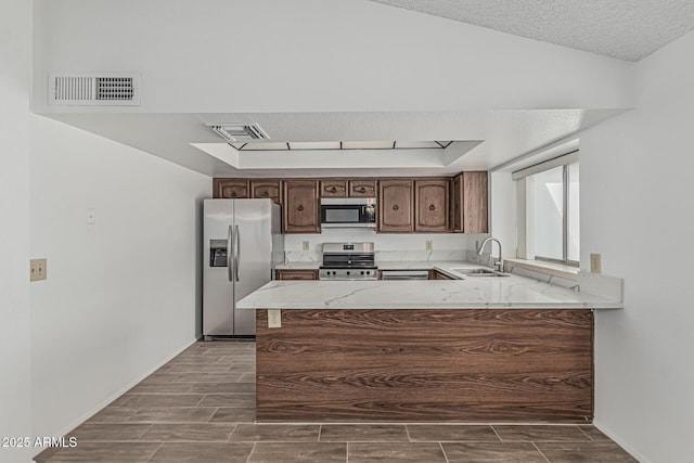 6701 W Monterey Way, Phoenix, AZ 85033 - kitchen with appliances with stainless steel finishes, a sink, a peninsula, wood tiled floors, and a textured ceiling