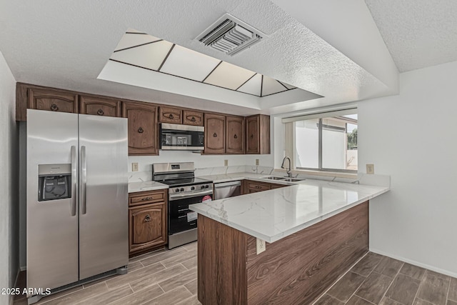 6701 W Monterey Way, Phoenix, AZ 85033 - kitchen featuring appliances with stainless steel finishes, a peninsula, a sink, wood finish floors, and light stone countertops
